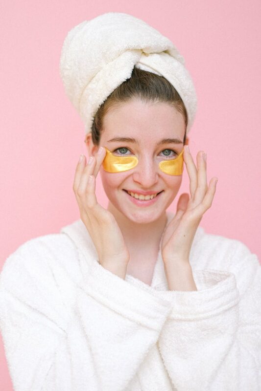 Smiling woman with eye patches touching face